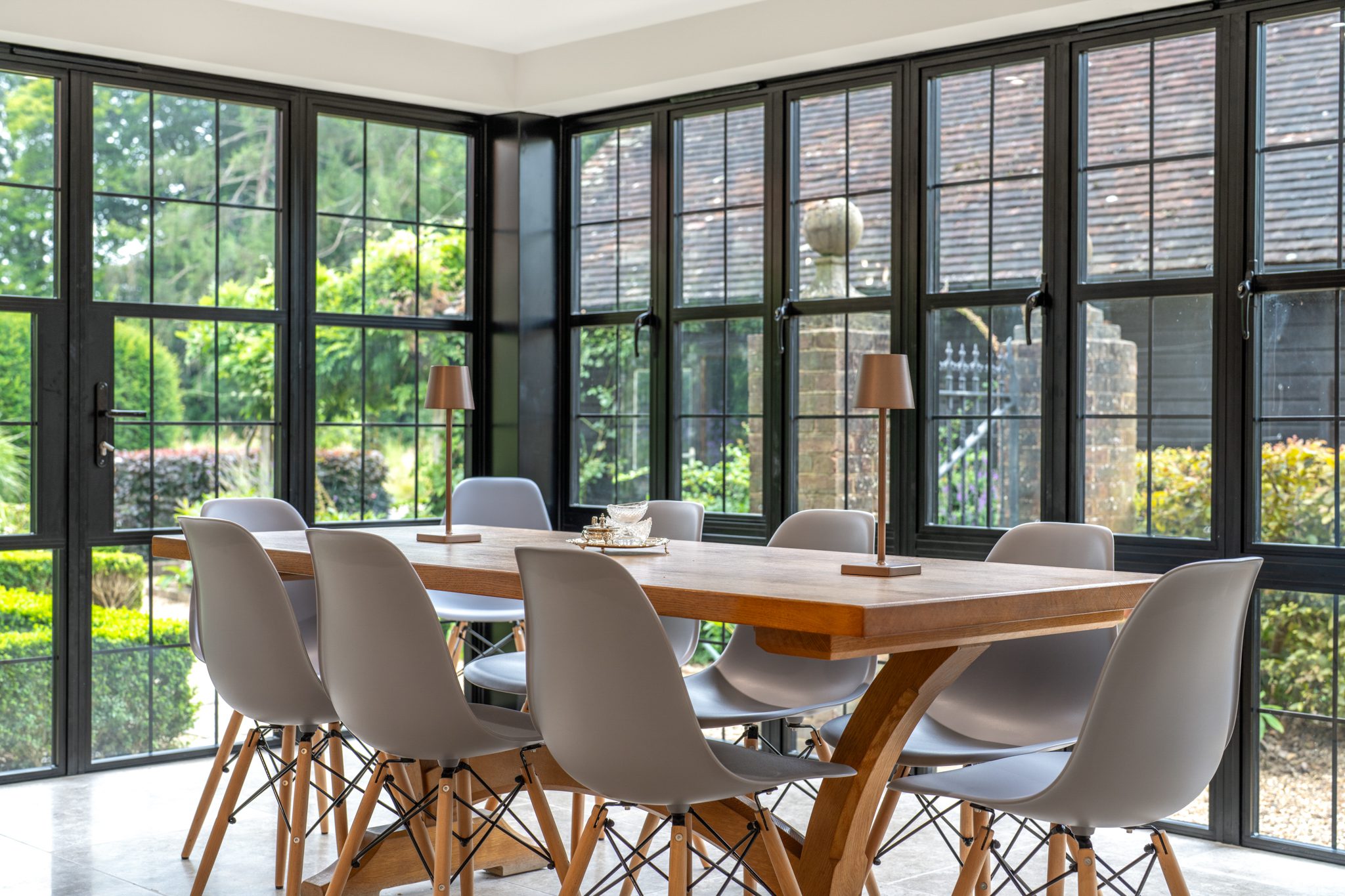 Dining room with black-framed windows overlooking a garden, photographed for a property listing