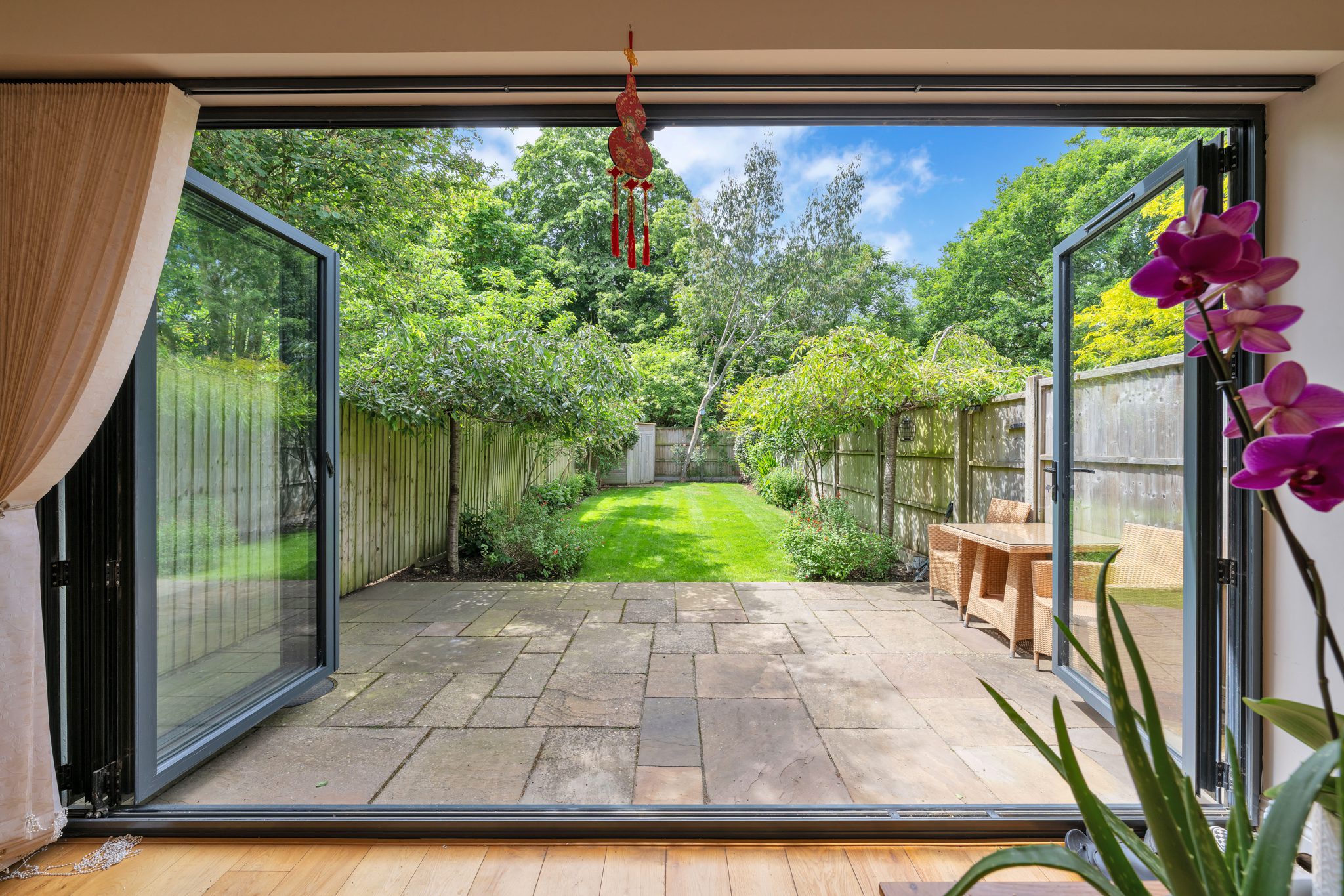 Open bifold doors leading from a property interior to a landscaped garden and patio